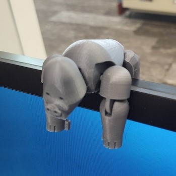 grey 3d printed bendy gorilla on top of a computer monitor