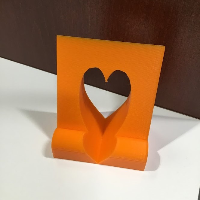 orange 3d printed phone stand with a heart cut out